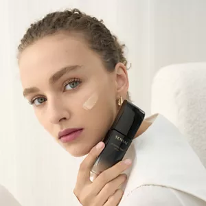 Person holding Glowing Base bottle in hand next to their face